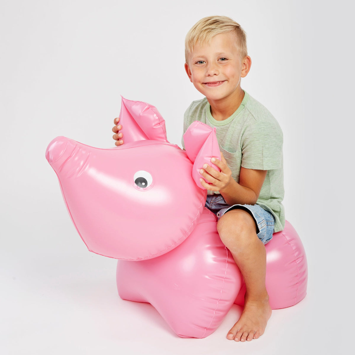 child sitting on an inflatable pink pig
